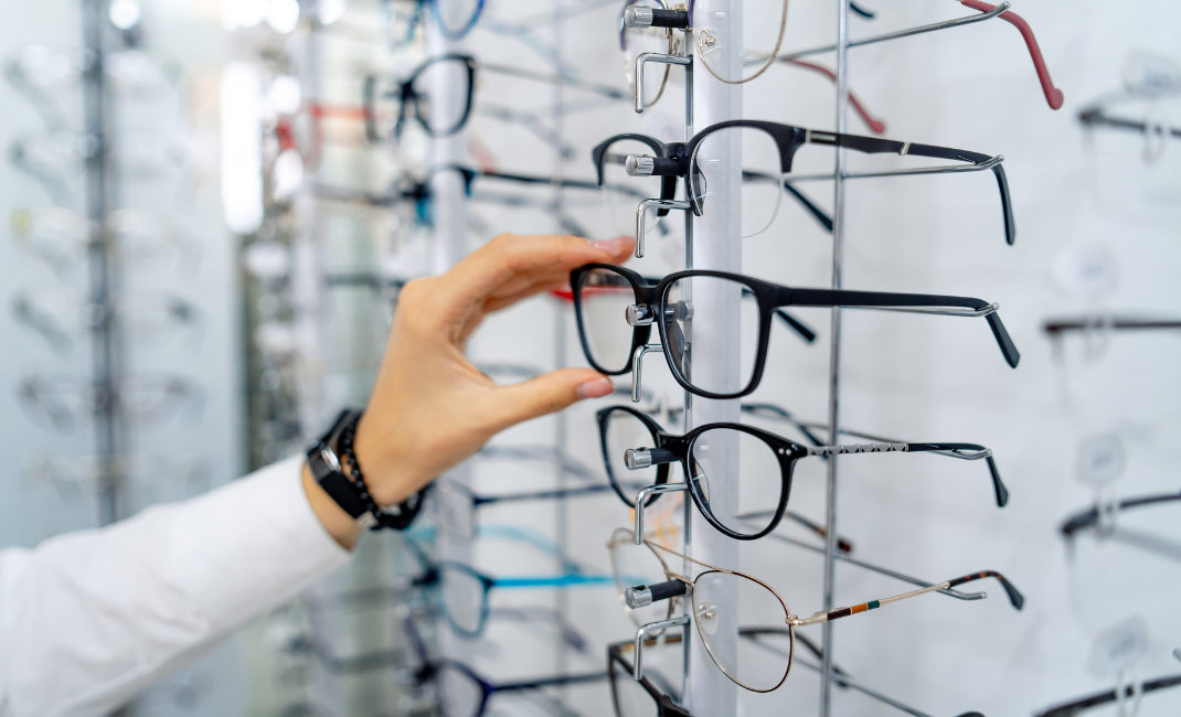 Kuvituskuva, kuvassa silmälasikehyksiä optikkoliikkeen hyllyssä.