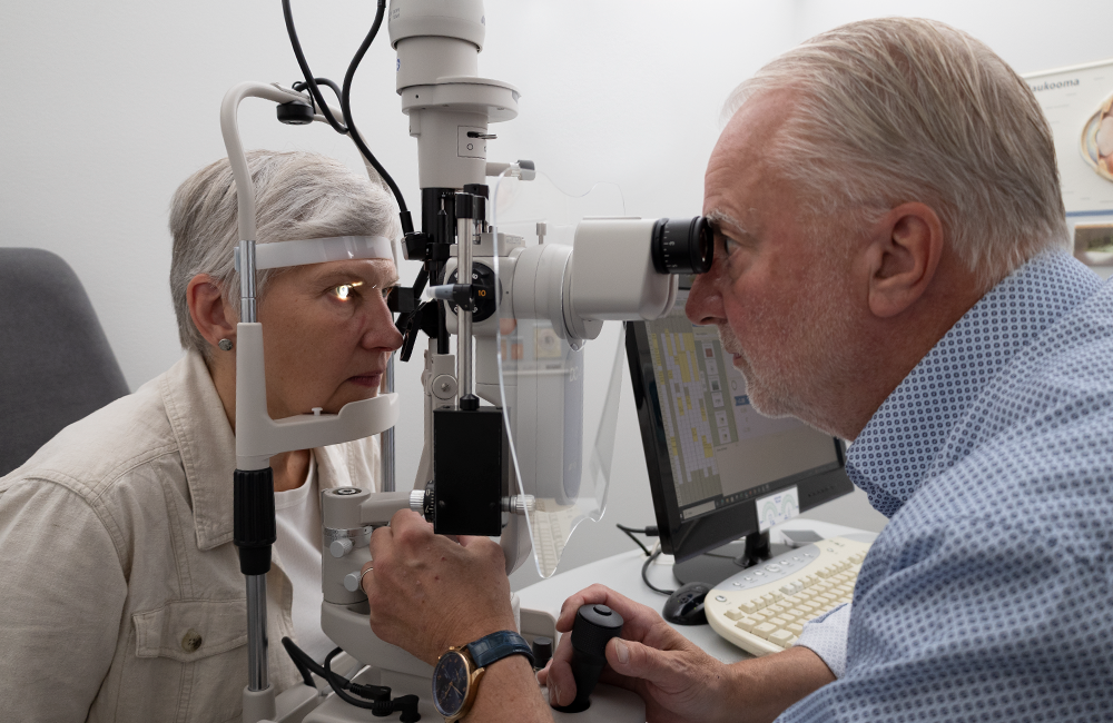 Optikko tutkii naishenkilön silmäterveyttä optikkoliikkeessä.