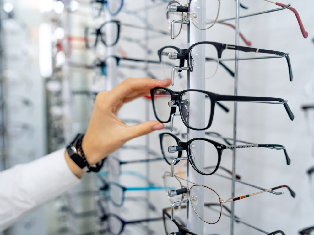 Henkilö valitsee silmälaseja optikkoliikkeessä.
