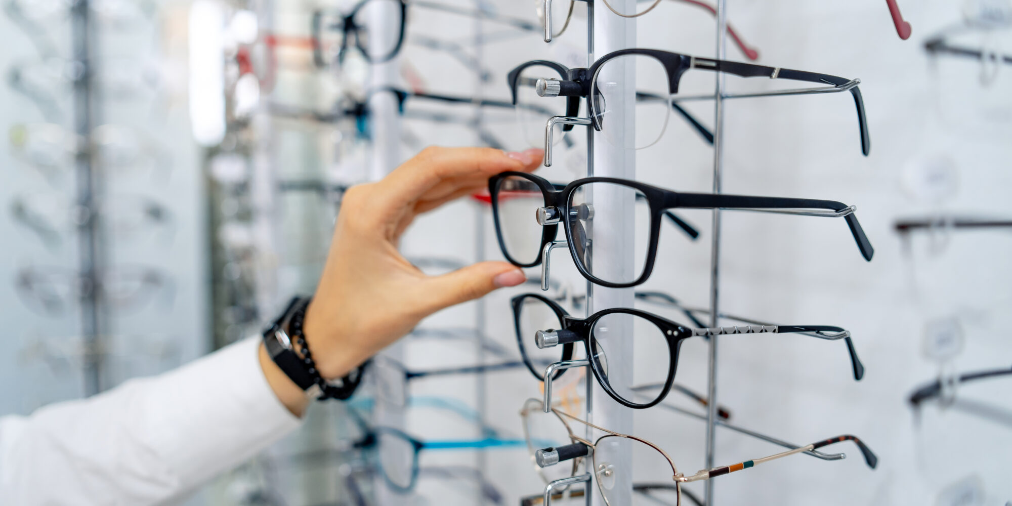 Henkilö valitsee silmälaseja optikkoliikkeessä.