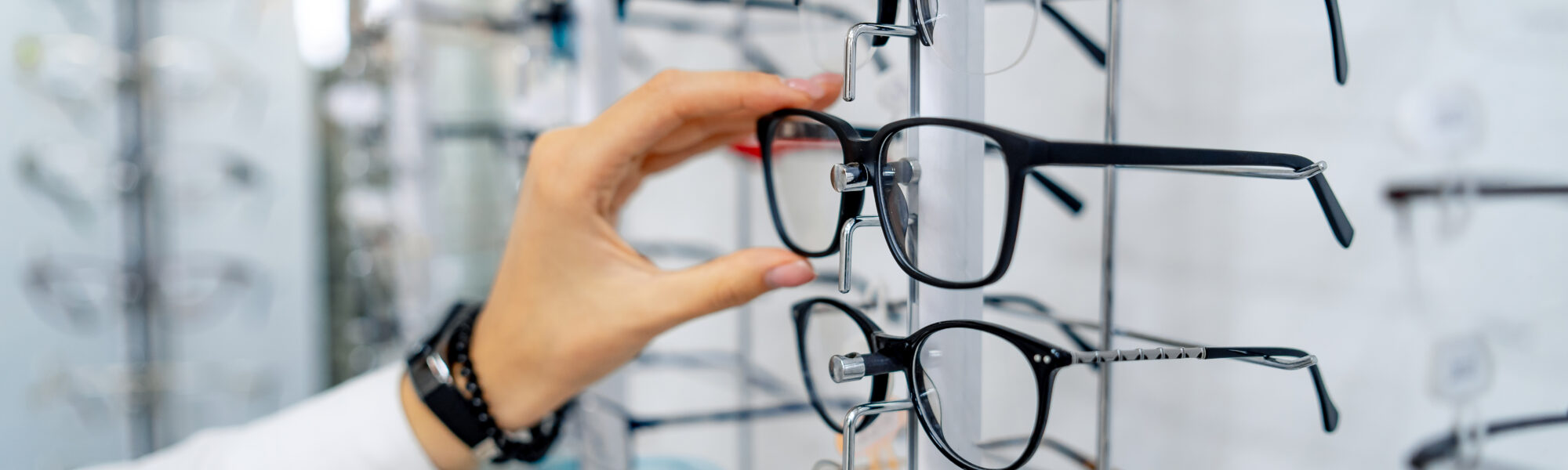 Henkilö valitsee silmälaseja optikkoliikkeessä.