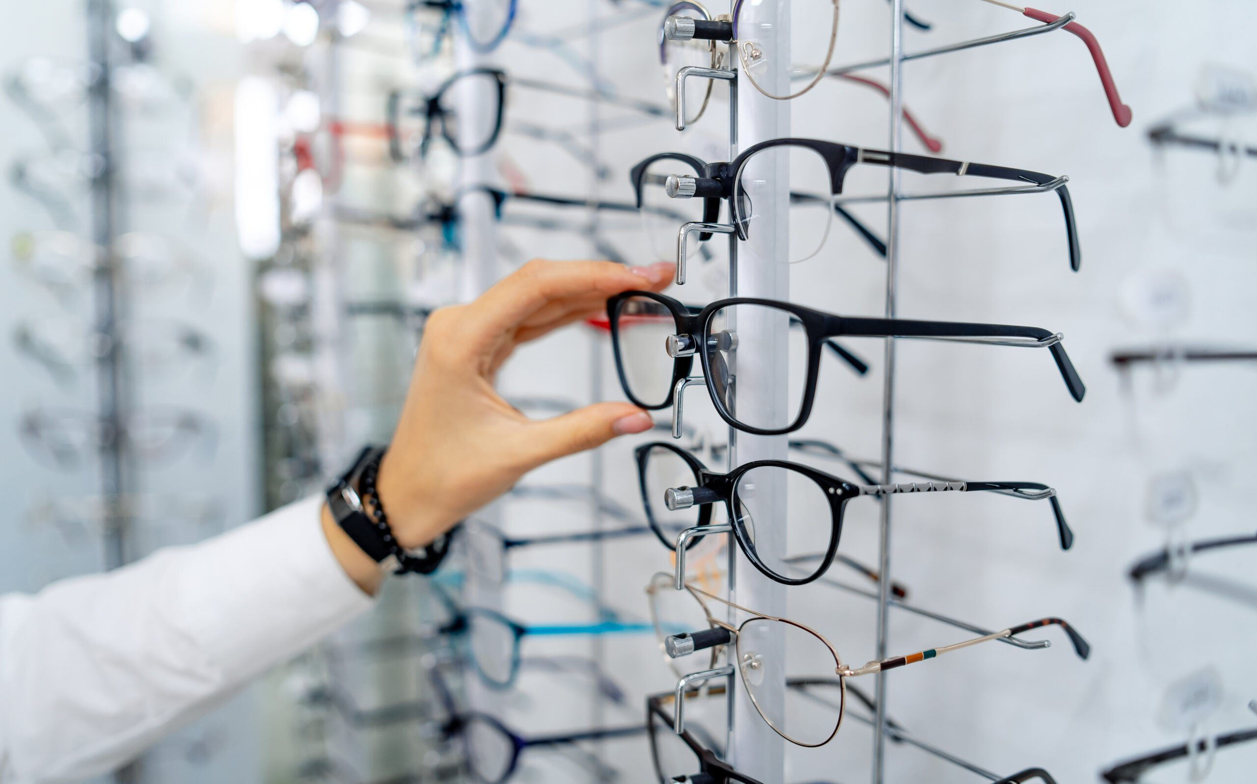 Henkilö valitsee silmälaseja optikkoliikkeessä.