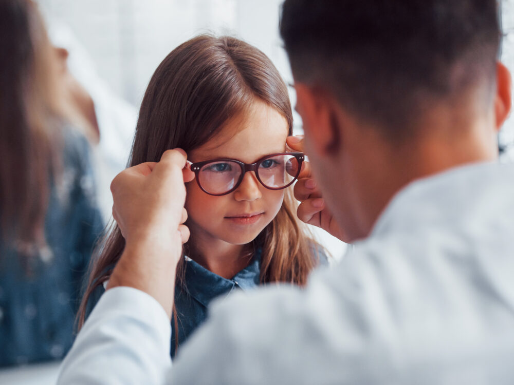 Optometristi sovittaa lapselle silmälaseja.