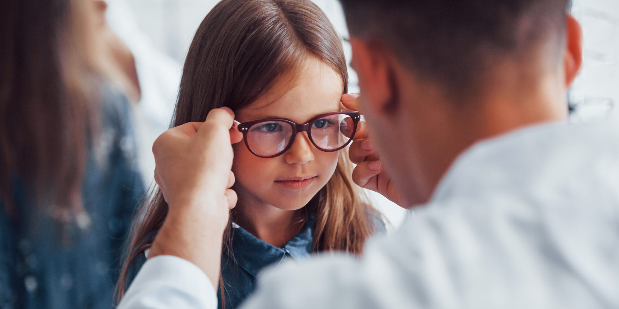 Optometristi sovittaa lapselle silmälaseja.