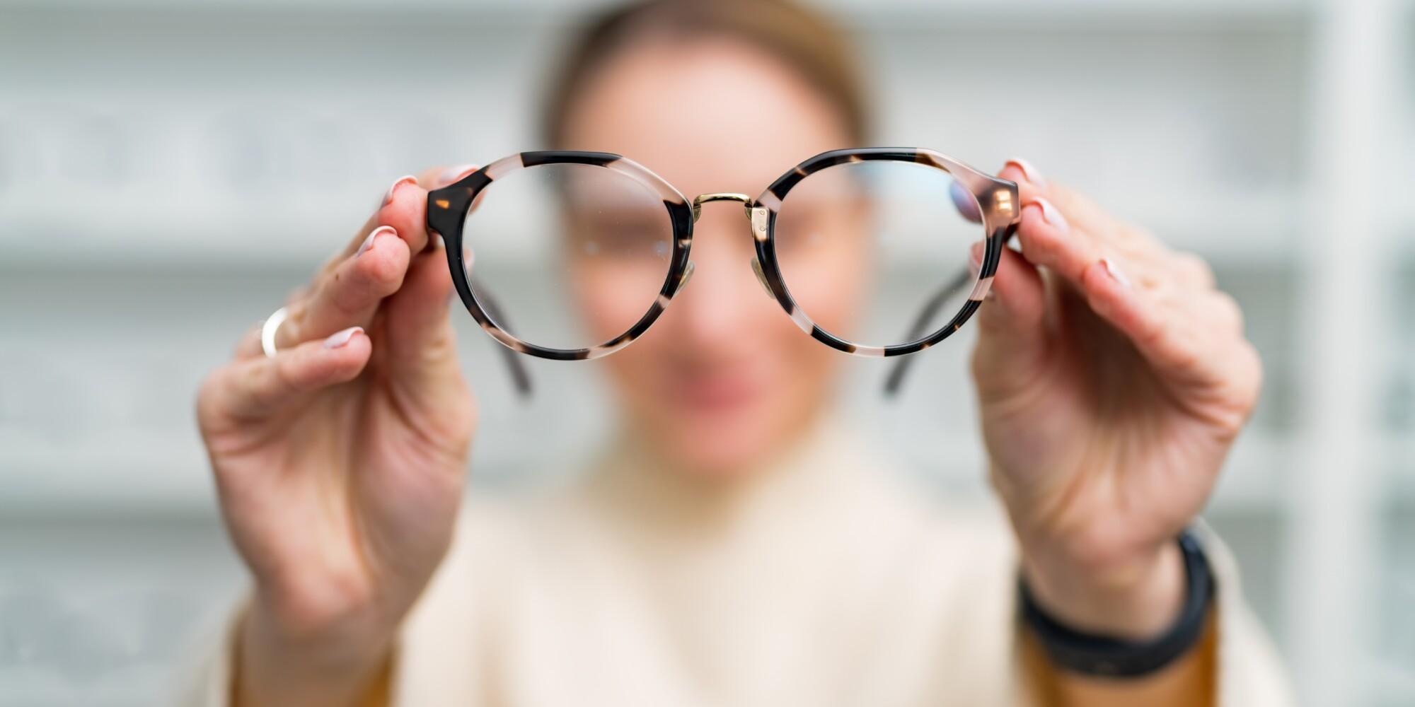 Nainen pitelee silmälaseja käsissään optikkoliikkeessä.