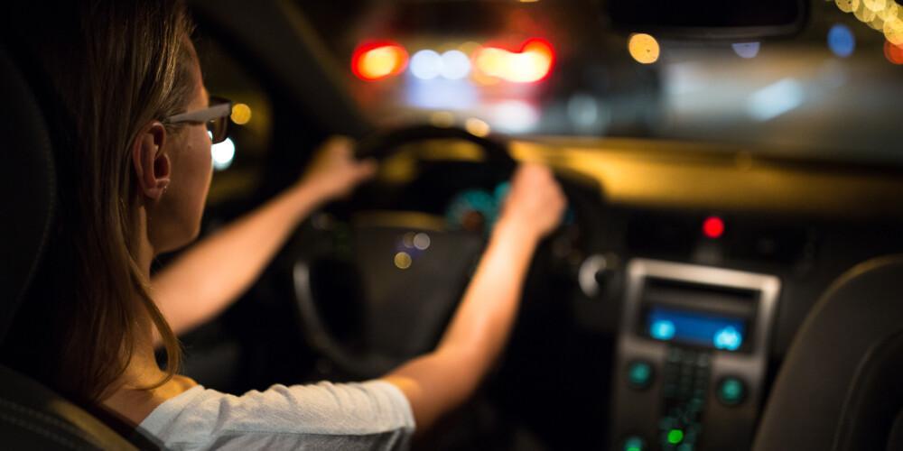 Nainen ajaa autoa pimeällä.