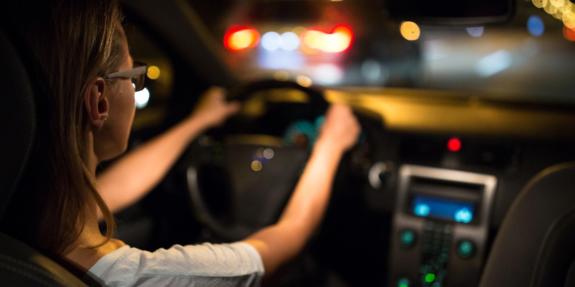 Nainen ajaa autoa pimeällä.